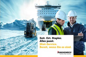Gabelstapler fahren auf einer verschneiten Eisfläche aus der Ladeluke eines grossen Schiffes heraus.